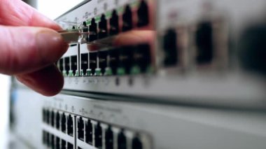 Network engineer connects Ethernet cable on computer switch close up zoom shot selective focus