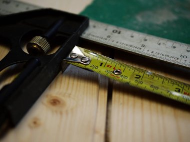 Carpenter tools square and tape measure on wooden background close up shot selective focus