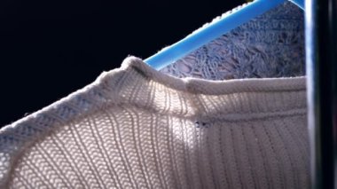 Winter wool jumper hangs on clothes hung on a rail close up 4k shot slow motion selective focus