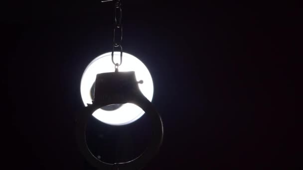 Handcuffs Hanging Bright Interrogation Light Medium Shot Selective Focus — Vídeos de Stock