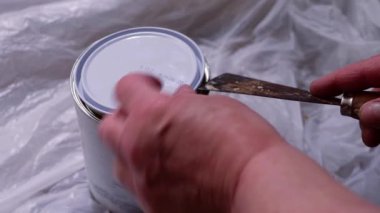 Decorating home opening a tin of white gloss paint close up 4k slow motion shot selective focus 