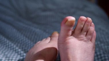 Ayaklar yatak yorganı üzerinde dinleniyor. 4k yavaş çekim seçici odak noktasını kapatın.