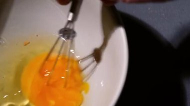 Yemek tarifi için çırpılmış yumurtaları yakın çekimde 4k yavaş çekimde seçici bir odak ile karıştırmak