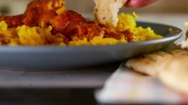 Pilau pilavlı Korma körili tavuğa naan ekmeği batırıyorum. Yavaş çekimde seçici odaklanma.