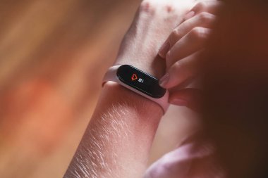 Genç kız akıllı saat bilekliğinde nabzına bakıyor.