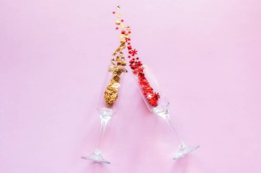 Şampanya bardakları ve konfeti konsepti Mutlu yıllar yeni yıl tatili pembe arka planda