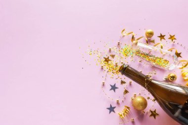Noel süslemeleri, oyuncaklar, bir şişe şampanya ve pembe arka planda konfeti ve yeni yıl için yeni yıl mesajı.