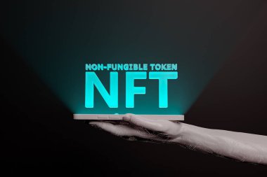 NFT illuminated word on the screen of a mobile phone held by an electronic hand. metaverse concept, nft, play to earn, crypto, blockchain and technology. 3d rendering clipart