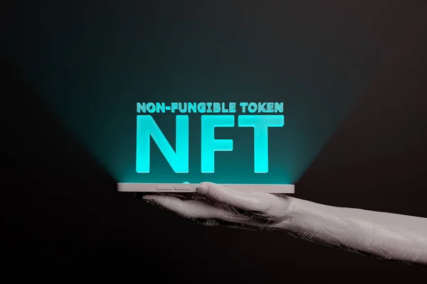 Elektronik bir el tarafından tutulan cep telefonunun ekranında NFT 'nin aydınlattığı kelime. Metaevren konsepti, nft, kazanmak için oyun, kripto, engelleme zinciri ve teknoloji. 3d oluşturma