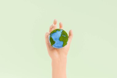 Stüdyoda, yeşil yosun ve mavi okyanuslarla kaplı küçük bir gezegeni tutan kişinin eli. 3d oluşturma