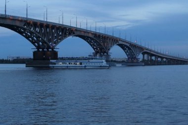 Zevkli bir motorlu gemi Volga boyunca Saratov nehrinin altından geçiyor.