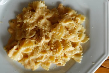 Beyaz tabakta rendelenmiş peynirli makarna