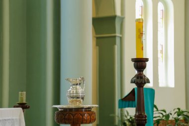 Illustrative scene of baptism in a Catholic church with baptismal font, water jug, candles and paschal candle clipart