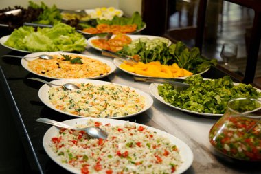 Tabakta servis edilecek çeşitli salatalarla dolu büyük bir masa.