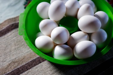 Masada yeşil kâse ve yumuşak yan aydınlatma şeklinde gruplanmış beyaz yumurtalar.