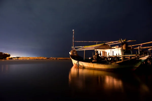 a beautiful landscape with a small boat at the water of a lake on a cloudy day.