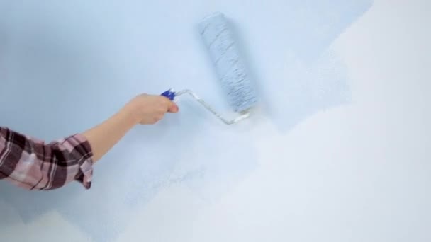 A young adult cheerful woman with blue paint using a roller. Repair and renovation of the design of home room apartment. DIY repair of the house. — Stock videók