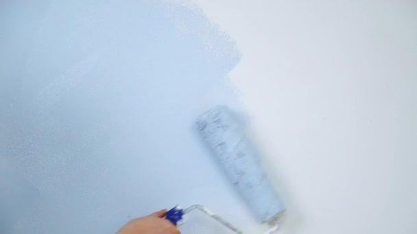 Una joven adulta alegre con pintura azul usando un rodillo. Reparación y renovación del diseño del apartamento de la habitación del hogar. DIY reparación de la casa. — Vídeos de Stock