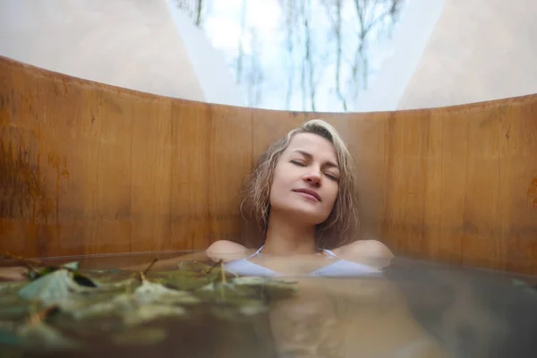 Молодая женщина зимой принимает горячую ванну в дубовой бочке. Паровая бочка и спа-центр. Стоковое Фото