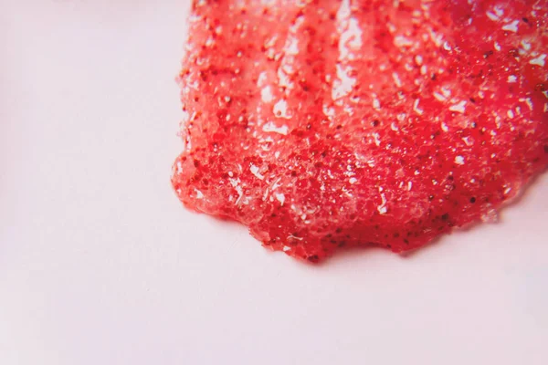 Red smears of scrub on pink background. Cosmetic product. Cleansing and exfoliating your skin. Copy space