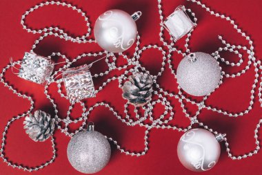 Kırmızı arka planda gümüş Noel süslemeleri.