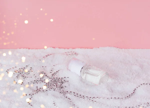 Producto cosmético facial en la nieve sobre fondo rosa con decoración navideña —  Fotos de Stock