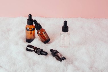 Pembe arka planda karda serum cam şişe. Sıvı deri ya da saç bakım ürünü. Doğal kozmetik konsepti. Ön görünüm, boşluğu kopyala