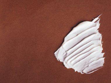 Pembe arka planda beyaz yüz kremi kokusu. Kozmetik ürün dokusu