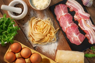 İtalyan Carbonara Makarnası için hazırlıklar. Domuz pastırmalı, siyah biberli, parmesanlı, el yapımı fettucine veya tagliatelle. Yemek ya da yemek tarifi. Ahşap arkaplan