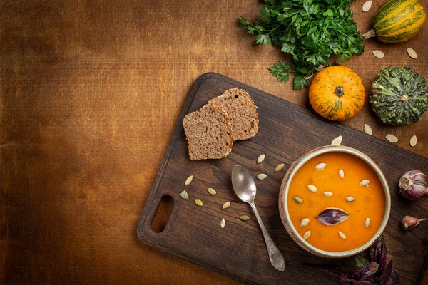 Pompoensoep Geserveerd Met Zaad Brood Peterselie Basilicum Een Snijplank Dieetvoedingsconcept — Stockfoto