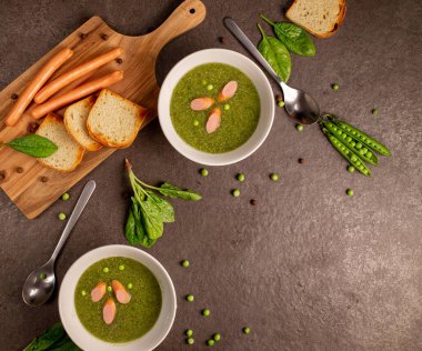 Mashed spring vegetable soup served with sausage and toast bred on a gray background, top view. Healthy vegetarian food concept. fragrant green soup from green peas, a bowl of soup peas on a table, a