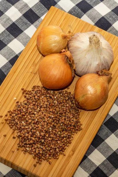 Rauwe Boekweit Drie Uien Knoflook Houten Loopgraaf Wit Zwarte Geruite — Stockfoto