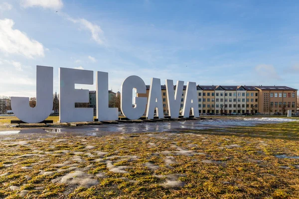 Güneşli kış gününde Letonya, Jelgava 'daki Post Island (Pasta Sala), Jelgava' daki Jelgava şehir isim tabelasına alçak açılı görüş. Jelgava şehir ismi işareti, buz, don, güneş ve mavi gökyüzü