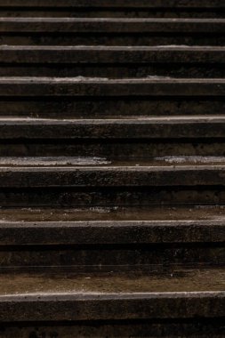 Kışın karanlık, ıslak, beton basamakların dikey yakın çekimi. Arka plan için eskimiş taş merdiven dokusu. Klasik merdiven şablonu. Şehirdeki şehir sınırları.  