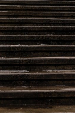 Kışın karanlık, ıslak, beton basamakların dikey yakın çekimi ve buz damlaları. Arka plan için eskimiş taş merdiven dokusu. Eski karanlık merdiven deseni. Şehirdeki ıslak şehir hatları.  