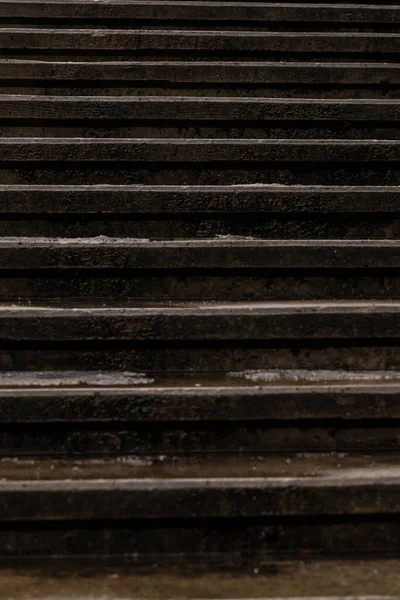 Kışın karanlık, ıslak, beton basamakların dikey yakın çekimi ve buz damlaları. Arka plan için eskimiş taş merdiven dokusu. Eski karanlık merdiven deseni. Şehirdeki ıslak şehir hatları.  