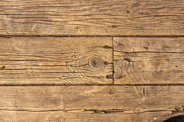 Esmer, eski ahşap parke zeminin yakın fotoğrafını çek. Açık hava sahnesi tahta sahnesi. Çivili sert ahşap arka plan. Yıpranmış dikey ahşap duvar. Ahşap doku arkaplanı 