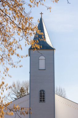 Hiiumaa, Estonya 'daki Baptist Lutheran kilise kulesinin açık mavi Krdla John' u ve bahar sabahının erken saatlerinde sarı Catkins 'in dikey fotoğrafı. Güneşli bir günde kilise kulesi ve fındık sarısı catkins.
