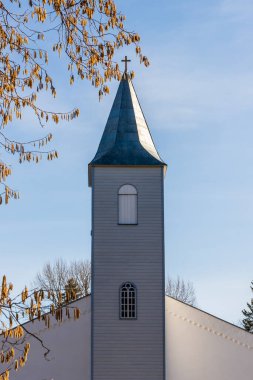 Açık mavi Krdla John, Hiiumaa, Estonya 'daki Baptist Lutheran kilise kulesi ve bahar günü erken saatlerde sarı katkinler. Güneşli bir günde kilise kulesi ve fındık sarısı Catkins dikey fotoğrafı..