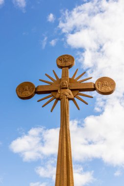 Litvanya 'nın başkenti Iauliai yakınlarındaki haç tepesinde büyük çapraz açık kahverengi ahşap marangozluk sanatının dikey fotoğrafı. Bulutlu gökyüzüne karşı Katolik haçı. 