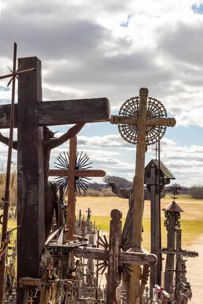 Vertical view from hill of crosses near iauliai, Lithuania to surrounded meadow in cloudy spring day. Back of the weathered wooden Catholic crosses on the hill.