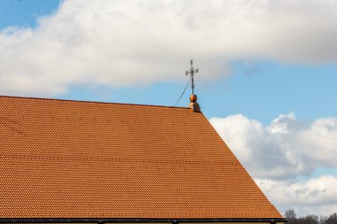 Baharın başında açık mavi ve beyaz gri bulutlu gökyüzüne karşı kırmızı taş katedralin çatısında metal bir haç. Çapraz kilise çatısı. Kaunas, Litvanya 'da haçı olan Katolik şapeli çatısı..