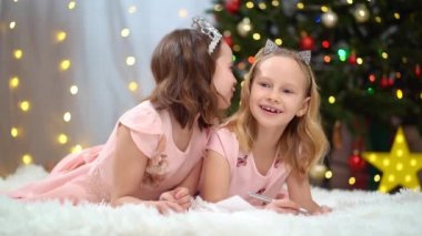 Pembe elbiseli iki mutlu küçük kız Noel Baba 'ya bir mektup yazıyor.