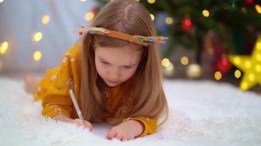 Komik küçük bir kız Noel ağacında Noel Baba 'ya mektup yazıyor..
