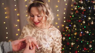 Bir adam Noel ağacında evlenme teklif ediyor. Nişan. Mutlu aşıklar.