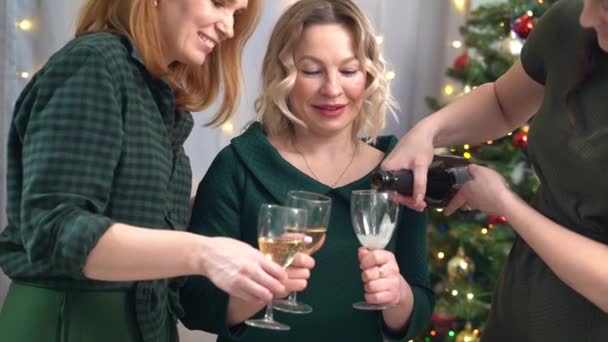 Three cheerful friends drink champagne at the Christmas tree. — Stock Video