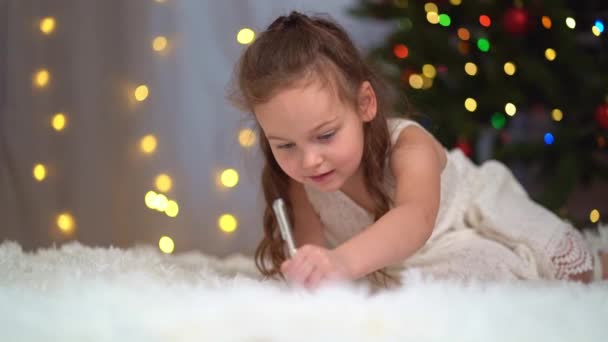 Cute brunetka mała dziewczynka pisze list do Świętego Mikołaja na choince. — Wideo stockowe