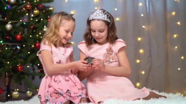 Pembe elbiseli mutlu küçük kızlar Noel ağacında hamsterla oynuyorlar..