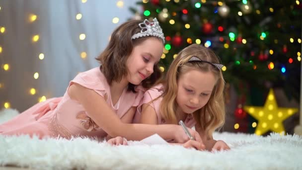 Deux belles et heureuses petites filles en robes roses au sapin de Noël. — Video