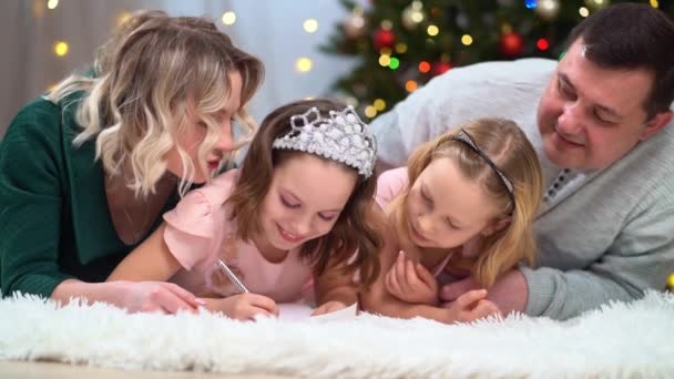 Une famille heureuse écrire une lettre au Père Noël au sapin de Noël. — Video